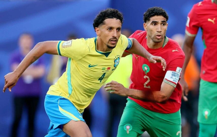 Two soccer players one in yellow Brazil kit and one in red Morocco kit chase the ball in a crowded match  trybalnews