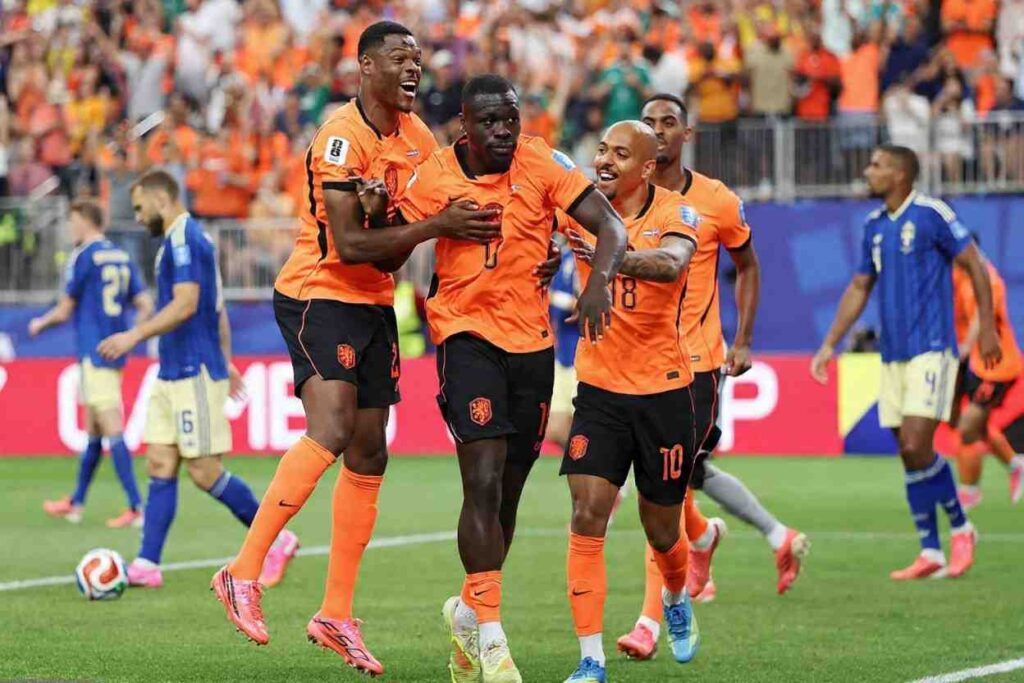 Netherlands forward Brian Brobbey wearing orange jersey number 19 celebrates his first goal with teammates during the FIFA World Cup 2026 Group F match vs Sweden Hes surrounded by 3 Dutch players in orange kits all smiling and embracing on the pitch Sweden players in blue jerseys walk in the background with fans in orange filling the stadium stands  trybalnews