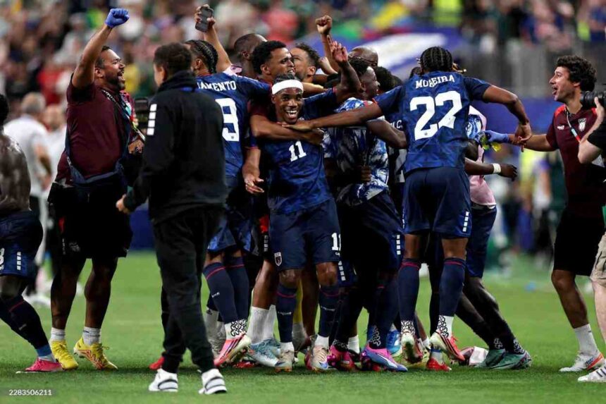 Cabo Verde players in dark blue kits with white numbers celebrate on the pitch after a 0 0 draw Player 11 wearing a white headband smiles and is hugged in the center with teammate 22 MOREIRA to his right and 9 MENDES behind him A staff member in a maroon shirt raises a blue gloved fist on the left and another staff member holds a camera on the right 2026 FIFA World Cup Group H match between Cabo Verde and Saudi Arabia on June 26 2026 at Houston Stadium in Houston Texas A blurred crowd fills the stadium background  trybalnews