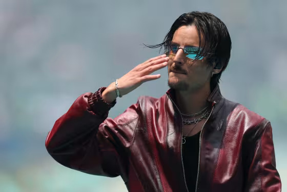 Man in a red leather jacket and sunglasses shielding his eyes with his right hand looking off to the side  trybalnews