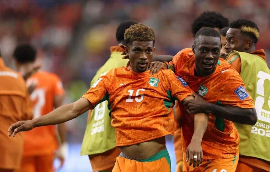 Cote dIvoire midfielder Amad Diallo wearing an orange 15 Puma kit with green accents and curly brown hair celebrates with his mouth open and arm outstretched Teammates in matching orange kits including 20 surround him with big smiles after scoring Cote dIvoires first goal This is during the FIFA World Cup 2026 Round of 32 match between Cote dIvoire and Norway on June 30 2026 at Dallas Stadium in Arlington Texas The background shows a blurred crowd and a player in a green training bib  trybalnews