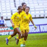 Three Edo Queen players in yellow uniforms celebrate together on a grassy field with empty stadium seats in the background  trybalnews