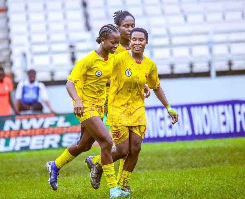 Three Edo Queen players in yellow uniforms celebrate together on a grassy field with empty stadium seats in the background  trybalnews