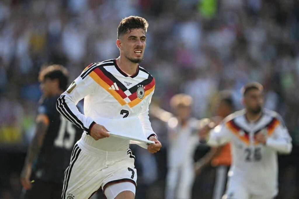 Havrertz Trybal News Germany forward Kai Havertz wearing a white 7 Germany kit with the black red and gold diagonal stripe and Adidas branding celebrates after scoring Germanys first goal He is running with his jersey pulled up slightly in both hands mouth open in a shout Behind him a Germany teammate in 26 runs to join the celebration while a Paraguay player in dark kit is blurred in the background The 2026 FIFA World Cup Round of 32 match between Germany and Paraguay was played on June 29 2026 at Boston Stadium in Foxborough A packed stadium of fans fills the stands behind them trybalnews