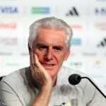 Hugo Broos white haired South Africa head coach in a light gray shirt sits at a press conference table with a microphone He rests his chin on his hand with a thoughtful expression Sponsor logos are blurred in the background Atlanta Stadium FIFA World Cup 2026 Group A June 18 2026  trybalnews
