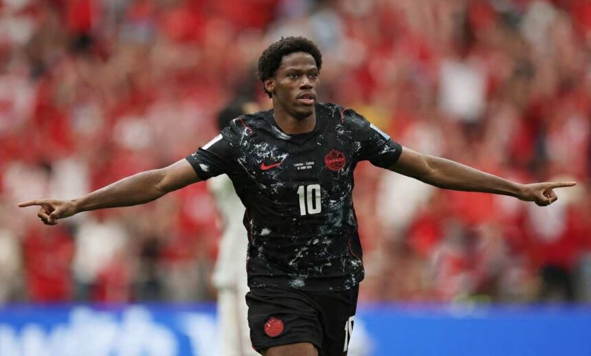 Jonathan David of Canada celebrates after scoring Canadas second goal vs Qatar at FIFA World Cup 2026 BC Place Vancouver June 18 2026 He wears a black Canada kit 10 with arms spread wide crowd blurred red behind him  trybalnews