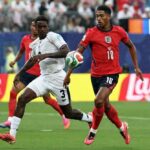 England midfielder Jude Bellingham wearing a red kit with number 10 and bright pink boots runs with the ball He is challenged by Panama defender Jose Cordoba number 3 in a white kit who is lunging to tackle Another England player in red is visible behind them The 2026 FIFA World Cup Group L match between Panama and England took place on June 27 2026 at New YorkNew Jersey Stadium in East Rutherford Lays advertising boards and a packed stadium crowd are in the background  trybalnews