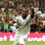 Mexico forward Julian Quinones wearing white 16 jersey with green and red trim matching white shorts and white wristbands celebrates after scoring He has short braided hair looks upward and points his right index finger to the sky while running on the green pitch Left arm is bent at his side FIFA World Cup 2026 Group A match between Czechia and Mexico at Mexico City Stadium Mexico City Mexico on June 24 2026 Mexico crest and Adidas logo visible on kit with blurred crowd in green behind him  trybalnews