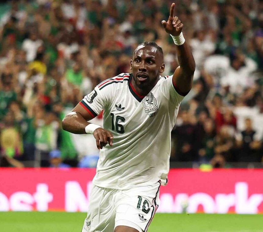 Mexico forward Julian Quinones wearing white 16 jersey with green and red trim matching white shorts and white wristbands celebrates after scoring He has short braided hair looks upward and points his right index finger to the sky while running on the green pitch Left arm is bent at his side FIFA World Cup 2026 Group A match between Czechia and Mexico at Mexico City Stadium Mexico City Mexico on June 24 2026 Mexico crest and Adidas logo visible on kit with blurred crowd in green behind him  trybalnews