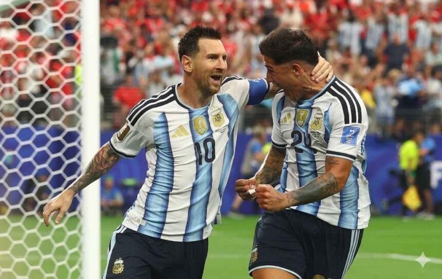 Argentina captain Lionel Messi 10 and teammate Enzo Fernandez 24 celebrate next to the goal post Messi has his arm around Fernandezs head and is shouting with joy Both wear Argentinas light blue and white striped jerseys and navy shorts The goal net is on the left and a blurred crowd fills the stands behind them at Dallas Stadium June 22 2026  trybalnews