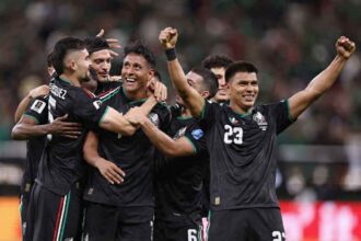 Mexico soccer players in black jerseys celebrate together on the field. Luis Romo, wearing #7, is at the center smiling as teammates surround him with arms raised after scoring Mexico’s first goal vs South Korea Korea at Guadalajara Stadium during the 2026 FIFA World Cup, June 18 2026.