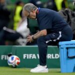 Uruguay head coach Marcelo Bielsa a gray haired older man with glasses sits hunched forward on a blue wheeled cooler at pitchside He wears a navy Uruguay tracksuit with MB on the leg white Adidas sneakers and a black smartwatch with his hands clasped and head bowed in a dejected pose A 2026 FIFA World Cup match ball and green FIFA WORLD CUP 26 hoarding are behind him 2026 FIFA World Cup Group H match between Uruguay and Spain on June 26 2026 at Guadalajara Stadium in Zapopan Mexico Staff in yellow vests and a camera operator are blurred in the background  trybalnews