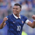 Footballer in a blue France jersey with number 10 celebrates with fists raised smiling on the pitch  trybalnews