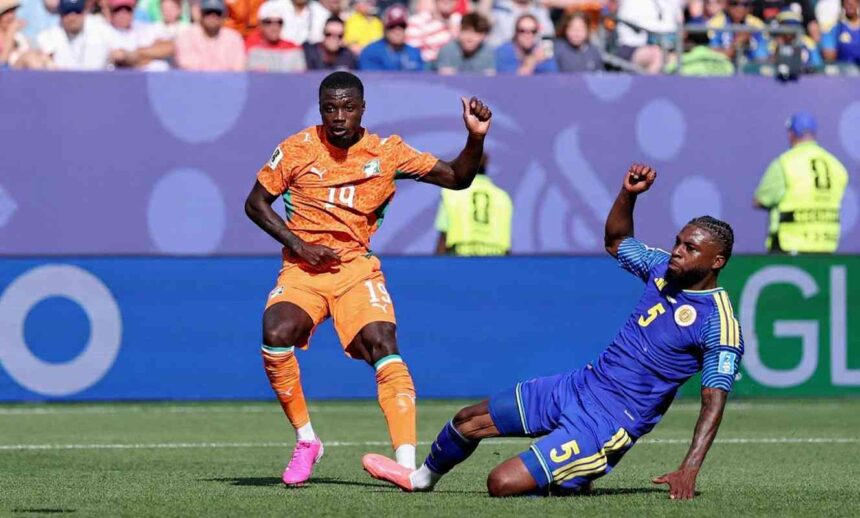 Cote dIvoire forward Nicolas Pepe wearing orange 19 Puma jersey orange shorts orange socks and pink football boots controls the ball on the pitch He is leaning forward with his right arm slightly out for balance as a Curacao defender in blue 5 kit slides on the ground beside him The match ball is airborne to Pepes left FIFA World Cup 2026 Group E match between Curacao and Cote dIvoire at Philadelphia Stadium Philadelphia Pennsylvania on June 25 2026 Cote dIvoire crest and Puma logo visible on kit  trybalnews