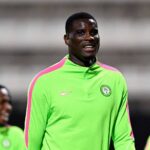 Footballer in neon green training top with pink stripes on the shoulders smiling on the field  trybalnews