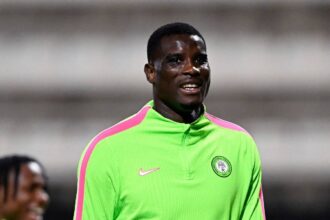 Footballer in neon green training top with pink stripes on the shoulders, smiling on the field.