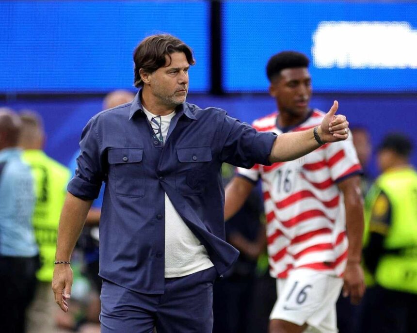 Male coach in blue outfit giving a thumbs up on a soccer field players and security in the background  trybalnews
