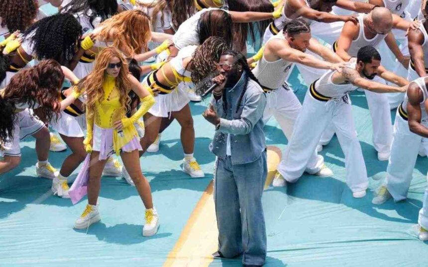 Burna Boy in a blue denim suit sings into a microphone on a turquoise stage surrounded by dancers in white and yellow outfits at the FIFA World Cup Opening Ceremony  trybalnews