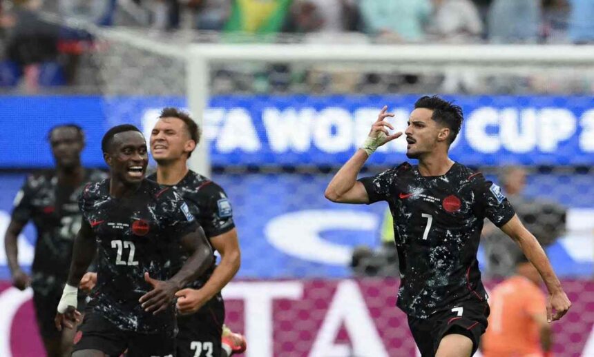Canada midfielder Stephen Eustaquio wearing a black kit with white speckled pattern red trim and number 7 celebrates on the right side of frame He raises his right hand with fingers pointing to his temple while shouting Teammates in matching black Canada kits including number 22 run toward him celebrating The 2026 FIFA World Cup Round of 32 match between South Africa and Canada took place on June 28 2026 at Los Angeles Stadium in Inglewood A FIFA WORLD CUP advertising board and goal net are visible in the background  trybalnews