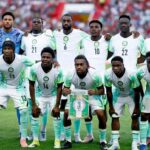 Nigeria national football team Super Eagles posing for a group photo on the field in white and green kits with a banner held by the center player  trybalnews