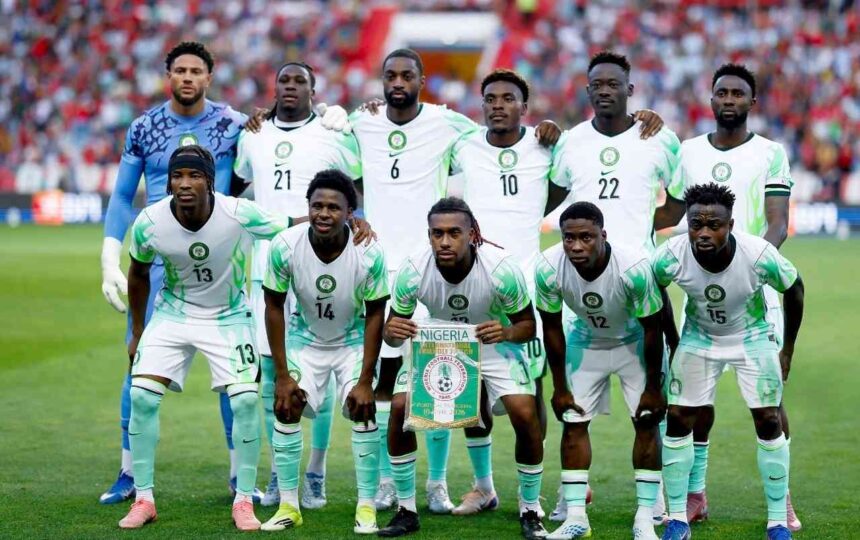 Nigeria national football team Super Eagles posing for a group photo on the field in white and green kits with a banner held by the center player  trybalnews