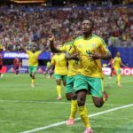 South African footballer Teboho Mokoena celebrates with arms raised after scoring a penalty kick He wears a green and yellow South Africa jersey The FIFA World Cup 2026 match between Czechia and South Africa is at Atlanta Stadium June 18 2026 Crowd and stadium visible in background  trybalnews