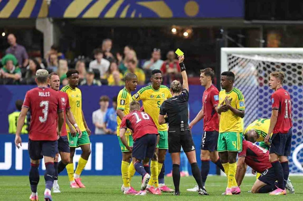 Referee Tori Penso in black uniform holds up a yellow card to Bafana Bafana defender Thalente Mbatha in yellow jersey Both teams and the referee are on the pitch at Atlanta Stadium during Czechia vs South Africa FIFA World Cup 2026 Group A June 18 2026  trybalnews