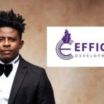 Portrait of a man in a black tuxedo and bow tie beside the EFFICIACY DEVELOPMENT PLC logo on a white panel  trybalnews