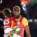 Two Galatasaray players celebrate hugging on the field with smiles and a flagcloth in hand  trybalnews