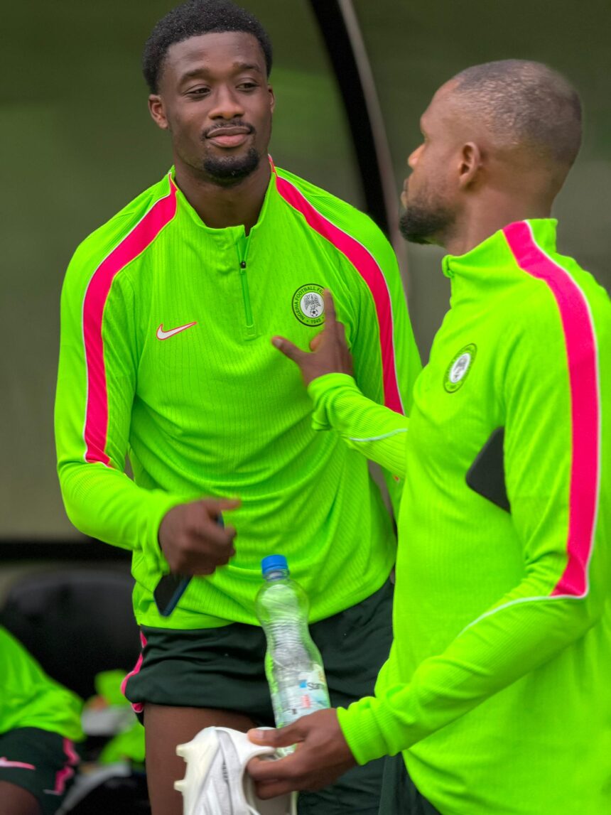 Two athletes in neon green training tops with pink stripes talk beside a water bottle during practice  trybalnews