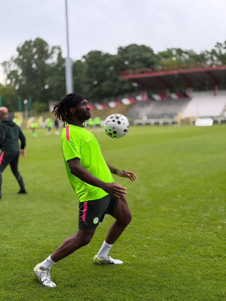 Soccer player in a neon green jersey and black shorts on a grassy field juggling a white ball mid air  trybalnews
