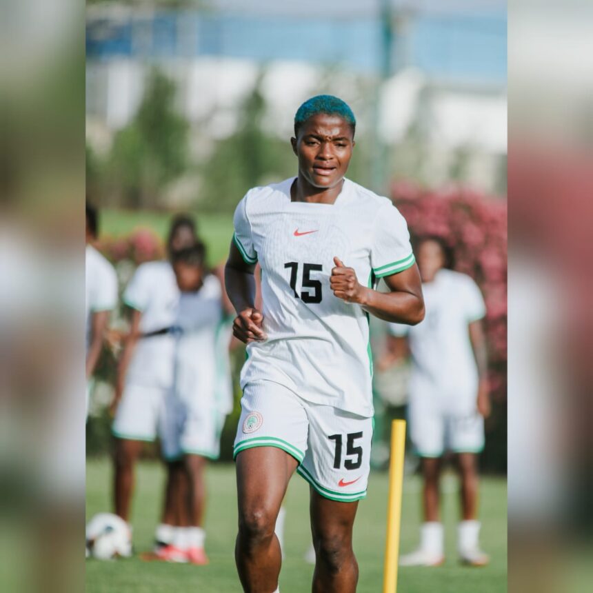 Soccer player with blue hair jogging on a field in a white kit with green trim number 15 visible on jersey  trybalnews
