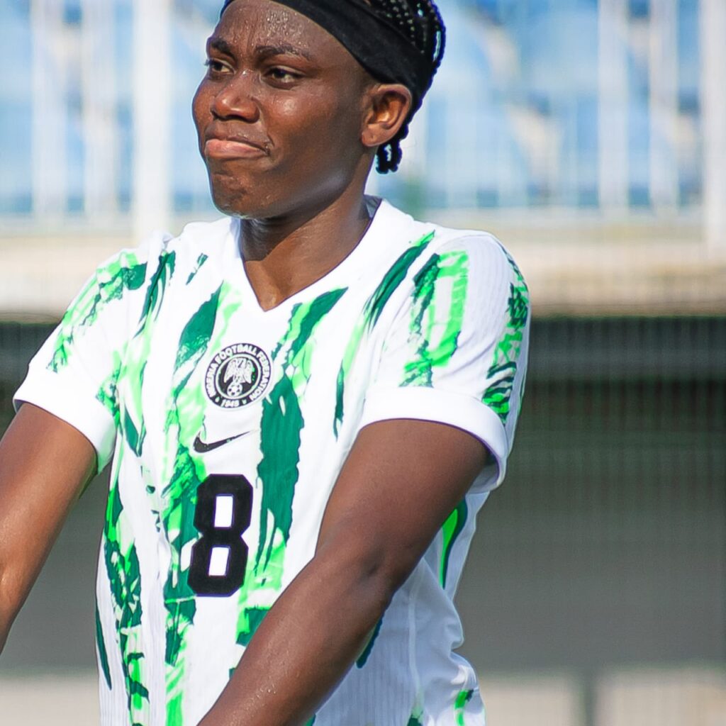 Female soccer player wearing a white jersey with green abstract patterns and the number 8 on a sunny field with a black headband  trybalnews