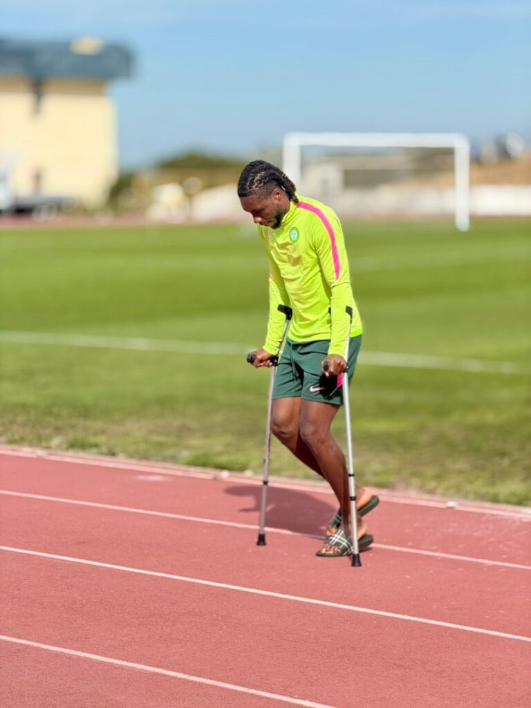 WhatsApp Image 20260606 at 195925 Trybal News Athlete using forearm crutches walking on a red track wearing neon yellow top and green shorts with a green field in the background trybalnews