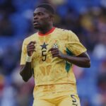 Soccer player in a yellow Ghana kit with number 5 running on a field with blurred blue seats in the background  trybalnews