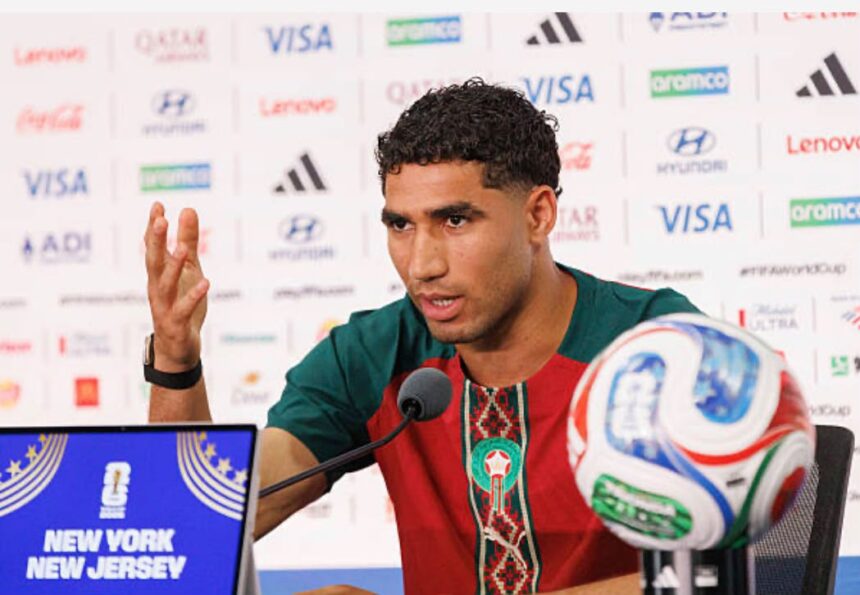 Male footballer at a press conference speaking into a microphone with a soccer ball on the table and a branded backdrop behind him  trybalnews