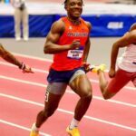 Auburn sprinter in red jersey running on a track wearing a bib with the name Kanyinsola Ajayi  trybalnews