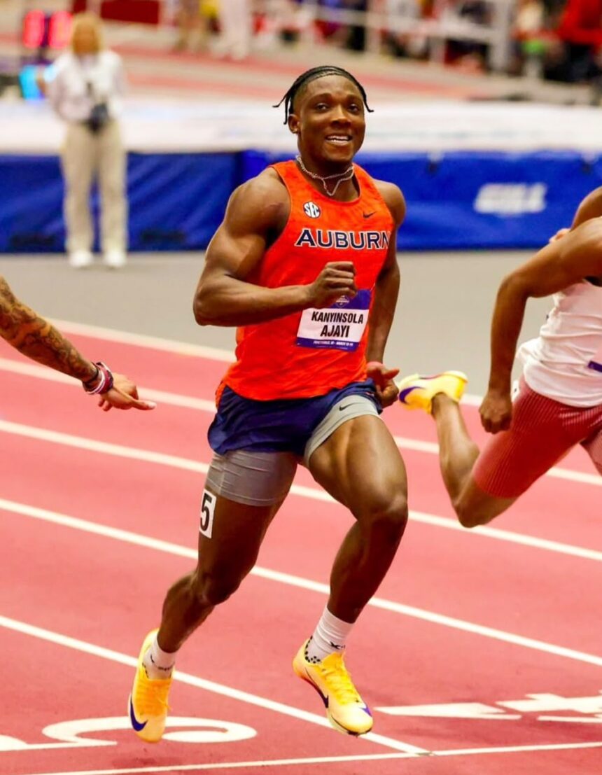Auburn sprinter in red jersey running on a track wearing a bib with the name Kanyinsola Ajayi  trybalnews