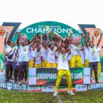 Group of young athletes on a podium celebrate winning the 202526 season raising medals and a trophy amid a champions backdrop  trybalnews