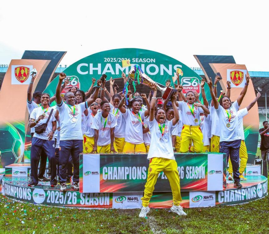 Group of young athletes on a podium celebrate winning the 202526 season raising medals and a trophy amid a champions backdrop  trybalnews
