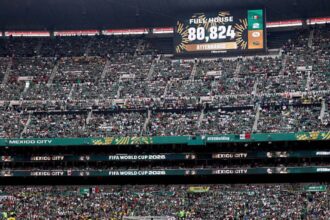 Crowd fills a large football stadium in Mexico City for a FIFA World Cup 2026 match, with a scoreboard displaying attendance 80,824 and 'Fuel House' text.
