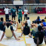 Basketball team seated on the court listening to coaches during a practice or meeting  trybalnews