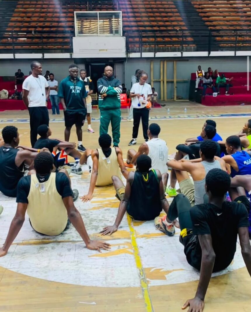 Basketball team seated on the court listening to coaches during a practice or meeting  trybalnews
