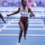 Female sprinter wearing a lavender kit crosses the track finish line with arms outstretched and a race bib reading AMUSAN  trybalnews