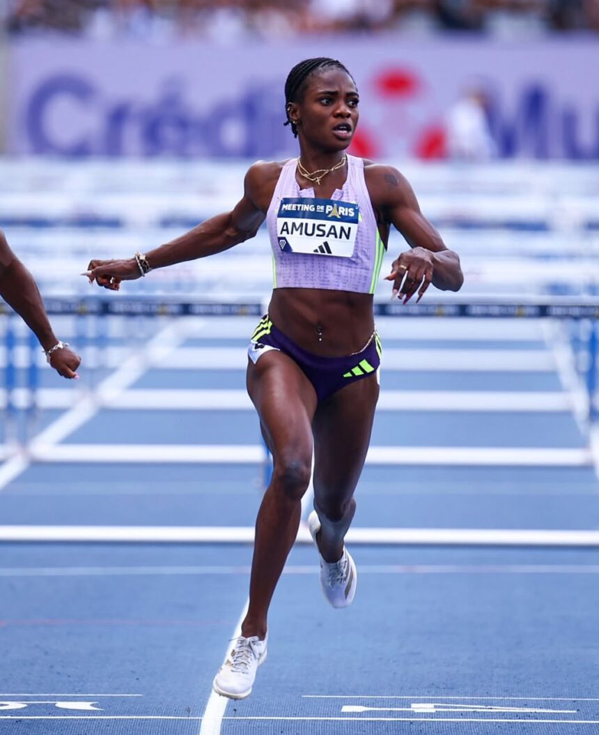 Female sprinter wearing a lavender kit crosses the track finish line with arms outstretched and a race bib reading AMUSAN  trybalnews