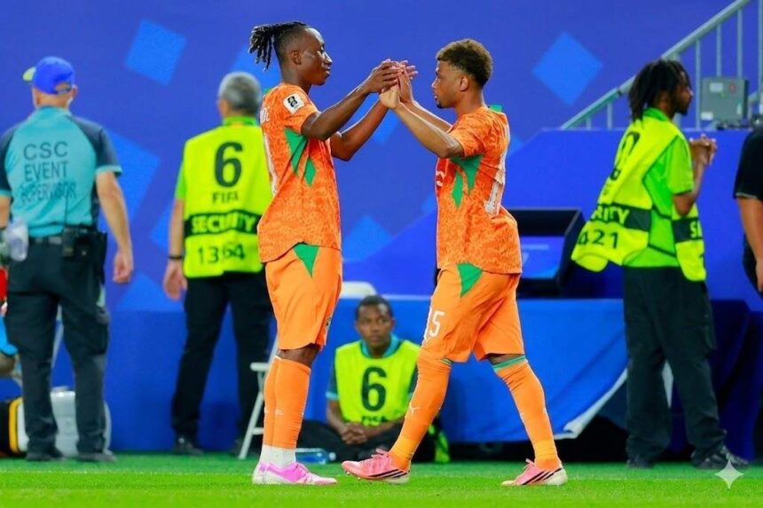 Two soccer players in orange kits share a high five on the field as staff and security stand in the background in a blue stadium setting  trybalnews