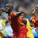 DR Congo forward Yoane Wissa wearing a red and yellow kit with number 20 celebrates with arms outstretched and fist clenched after scoring Teammates in yellow and blue training bibs celebrate around him The 2026 FIFA World Cup Group K match between DR Congo and Uzbekistan took place on June 27 2026 at Atlanta Stadium in Atlanta Georgia A blurred stadium crowd is visible in the background  trybalnews