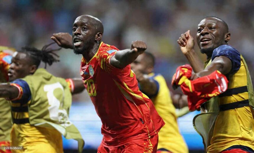 DR Congo forward Yoane Wissa wearing a red and yellow kit with number 20 celebrates with arms outstretched and fist clenched after scoring Teammates in yellow and blue training bibs celebrate around him The 2026 FIFA World Cup Group K match between DR Congo and Uzbekistan took place on June 27 2026 at Atlanta Stadium in Atlanta Georgia A blurred stadium crowd is visible in the background  trybalnews