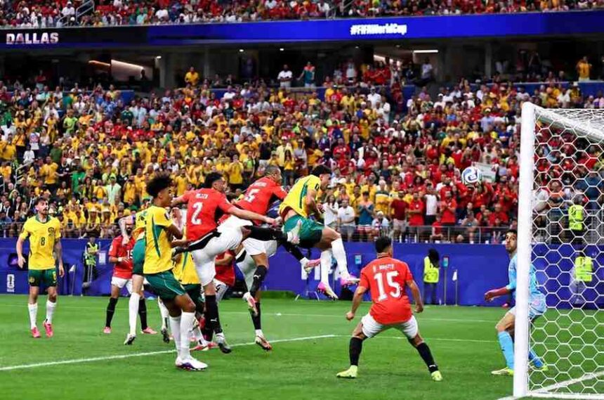Mohamed Hany of Egypt wearing a red jersey with number 2 attempts a defensive clearance in front of goal during the FIFA World Cup 2026 Round of 32 match between Australia and Egypt at Dallas Stadium in Arlington Texas on July 3 2026 The ball is in the air near the goal line as Australian players in yellow and green and other Egyptian players in red contest a header The score was leveled at 1 1 following an own goal A packed stadium crowd fills the background with DALLAS and FIFAWorldCup visible on the stadium signage  trybalnews