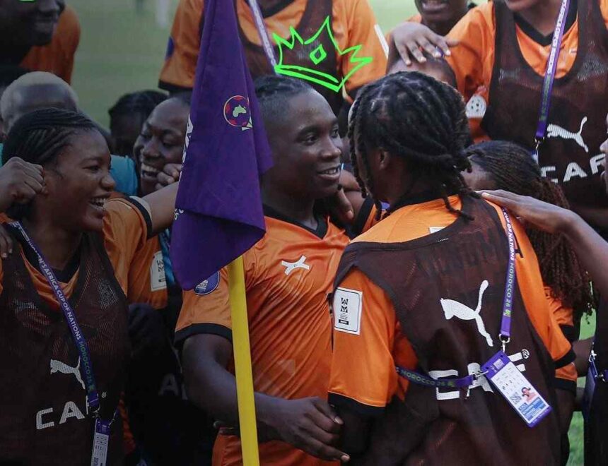 Group of soccer players in orange and brown uniforms celebrate with arms around each other a purple flag in the foreground  trybalnews